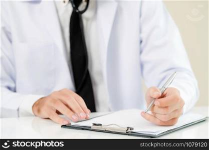 Doctor in hospital working and writing on paperwork. Healthcare and medical service concept.