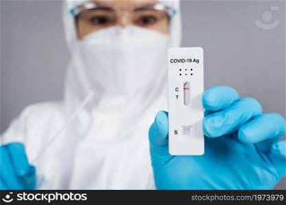 doctor in PPE suit holding Coronavirus(Covid-19) negative test result with Antigen Rapid Test kit (ATK)