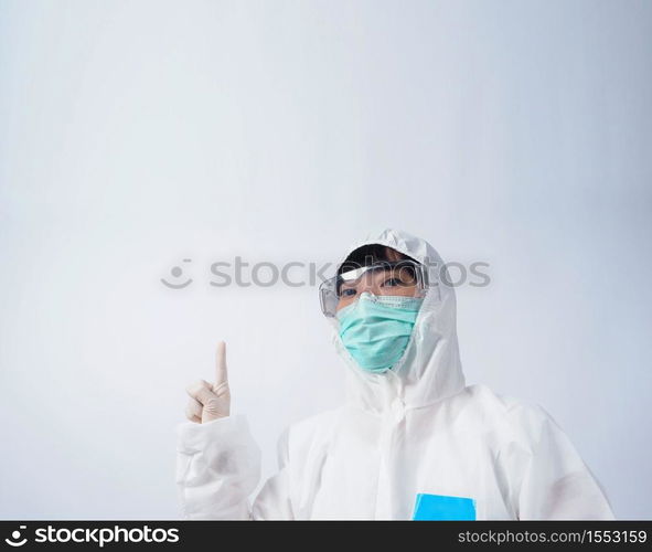 Doctor in PPE suit or Personal Protection Equipment point out to copy space and wearing white color medical rubber gloves and clear goggles glasses and green N95 mask to protect and fight pandemic virus