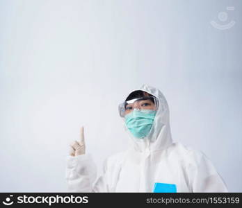 Doctor in PPE suit or Personal Protection Equipment point out to copy space and wearing white color medical rubber gloves and clear goggles glasses and green N95 mask to protect and fight pandemic virus