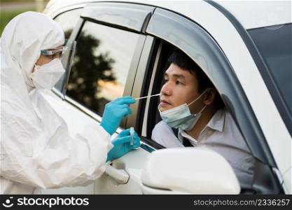 doctor in PPE suit test coronavirus covid-19  to man in car by nasal swab cotton, drive thru test fast track