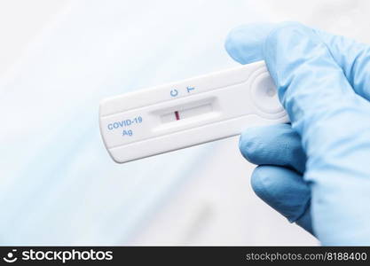 Doctor in protective gloves holding a negative result for COVID-19 with test kit for viral disease. 