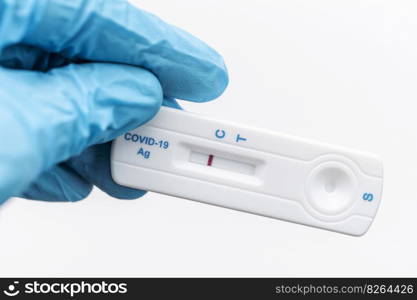 Doctor in protective gloves holding a negative result for COVID-19 with test kit for viral disease. 