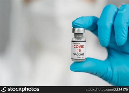 doctor in protective PPE suit holding Coronavirus  Covid-19  vaccine bottle