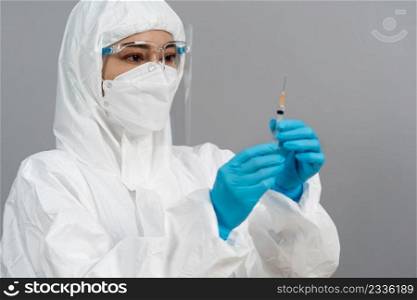 doctor in protective PPE suit holding syringe with Coronavirus  Covid-19  vaccine for injection test