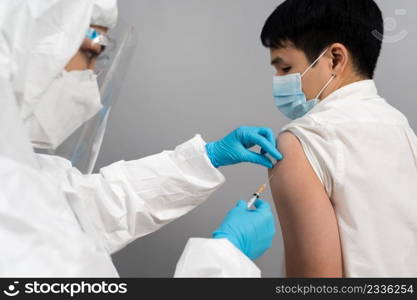 doctor in protective PPE suit syringe and using cotton before make injection to patient in medical mask. Covid-19 or coronavirus vaccine