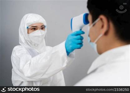 doctor in protective PPE suit using infrared thermometer measuring temperature with people, IR Thermoscan