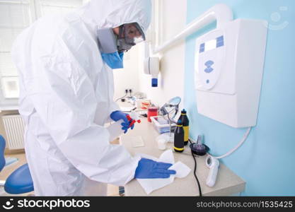 Doctor in protective suit uniform and mask cleans the laboratory. Coronavirus outbreak. Covid-19 concept.