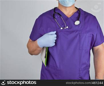 doctor in purple uniform and sterile latex gloves holds clipboard with a blank sheet of paper, gray background