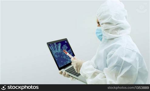 Doctor in white bioprotective suit and blue mask standing with his arm holding an open laptop with a virus on the screen and in the other hand holding a test tube with Covid-19 label on white background. Doctor in bioprotective suit and blue mask standing with his arm holding an open laptop with a virus on the screen and in the other hand holding a test tube with Covid-19 label on white background
