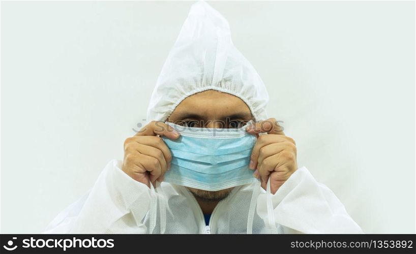 Doctor in white bioprotective suit holding a blue mask with his hands putting it on his face on white background. Doctor in bioprotective suit holding a blue mask with his hands putting it on his face on white background