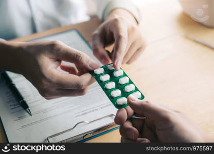 Doctor is pointing to drug tablet and introducing the properties of the painkiller to patient at office.