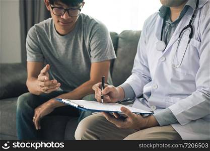 Doctor is recording the patient&rsquo;s information while the patient is explaining.