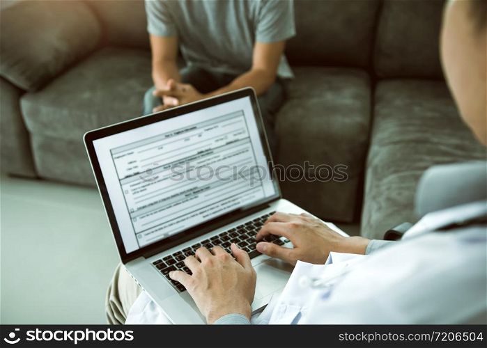 Doctor is using a laptop while typing the patient personal history record and giving advice about the patient home treatment.