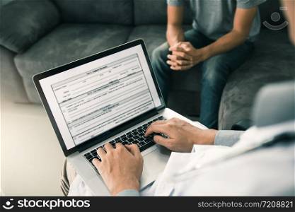 Doctor is using a laptop while typing the patient personal history record and giving advice about the patient home treatment.