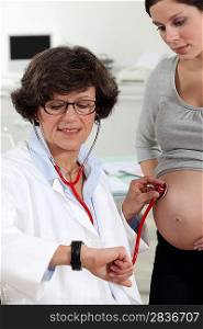Doctor listening to a pregnant woman&acute;s stomach