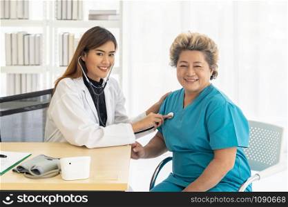 Doctor listens to elderly woman breath with a stethoscope at examination room office in hospital clinic.