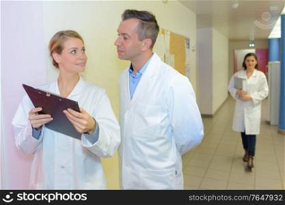 Doctor looking at clipboard in hospital corridor
