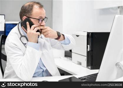 Doctor looking worried a desktop computer screen,, checking the results of a medical examination. High quality photography.. Doctor looking worried a desktop computer screen, checking the results of a medical examination.