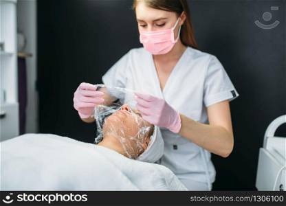 Doctor makes face mask, getting rid of wrinkles, cosmetology clinic. Facial skincare, rejuvenation procedure in spa salon, health care. Doctor makes face mask, getting rid of wrinkles