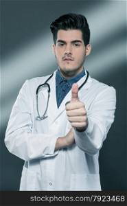 Doctor making positive thumb gesture over grey background