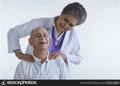 Doctor massaging old mans shoulders