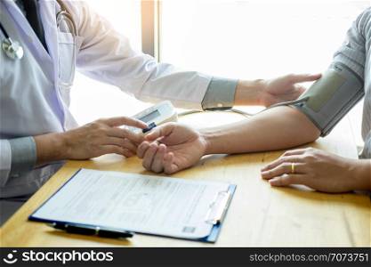 Doctor measuring and checking blood pressure of patient in hospital, Health care concept