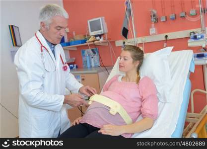 doctor measuring pregnant woman tummy at hospital