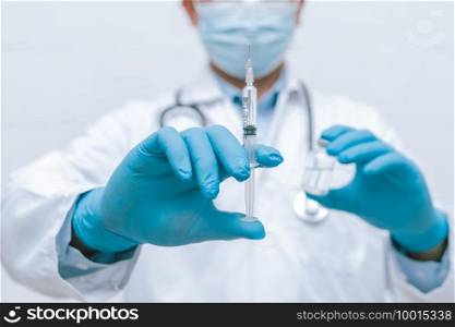 Doctor, nurse, scientist hand in blue gloves holding flu, measles, coronavirus, covid-19 vaccine disease preparing vaccination shot, medicine and drug concept.
