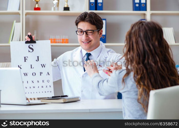 Doctor optician with letter chart conducting an eye test check