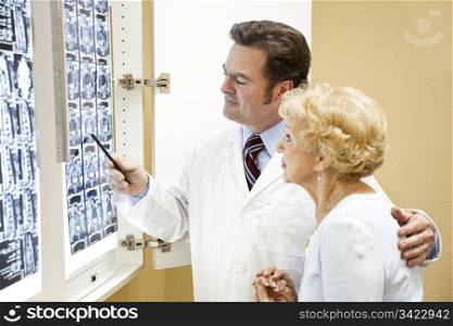 Doctor or chiropractor discussing the results of a cat scan of the spine with an elderly patient.