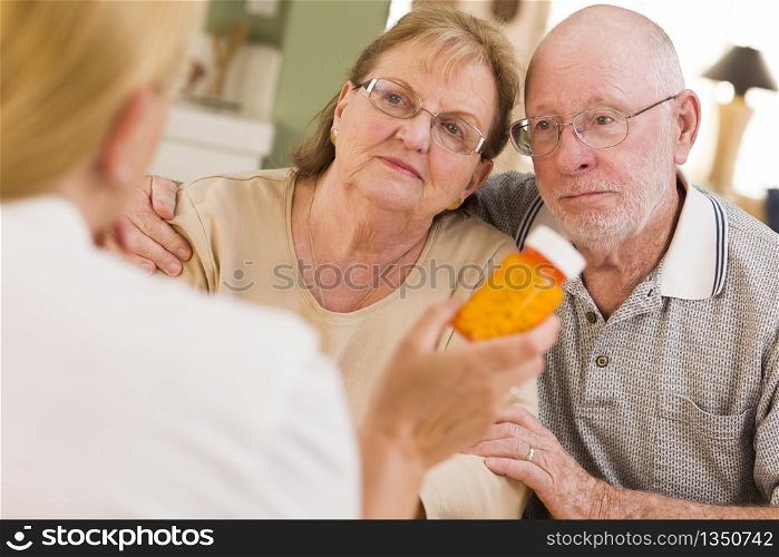 Doctor or Nurse Explaining Prescription Medicine to Attentive Senior Couple.