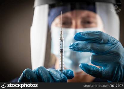 Doctor or Nurse Holding Medical Syringe with Needle AGainst Dark Background.