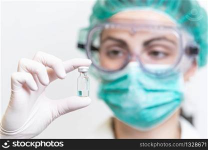 Doctor or nurse in protective gloves holding vaccine vial for Coronavirus outbreak pandemic. Medicine and drug concept . . Doctor or nurse in protective gloves holding vaccine vial for Coronavirus outbreak pandemic. Medicine and drug concept.