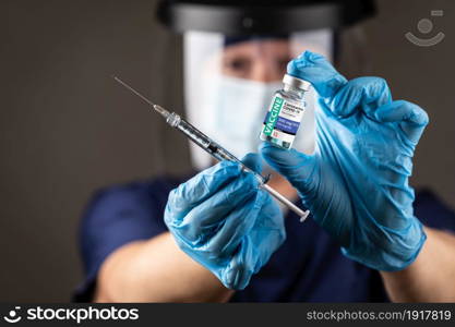 Doctor or Nurse Wearing Surgical Gloves Holding Vaccine Vial and Medical Syringe.