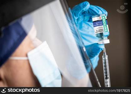 Doctor or Nurse Wearing Surgical Gloves Holding Vaccine Vial and Medical Syringe.