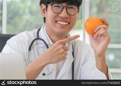 Doctor or nutritionist hold orange and Point your finger at the orange. in and smile in clinic. Healthy diet. Concept of nutrition food as a prescription for good health, fruit is medicine