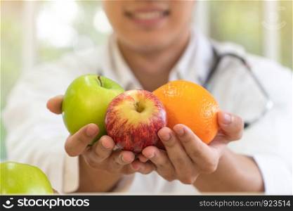 Doctor or nutritionist holding fresh fruit (Orange, red and green apples) and smile in clinic. Healthy diet Concept of nutrition food as a prescription for good health, fruit is medicine