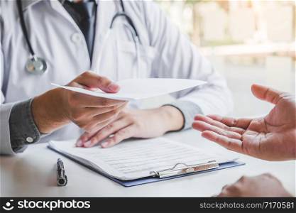 Doctor or physician writing diagnosis and giving a medical prescription to male Patient
