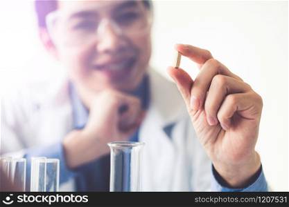 Doctor or scientist holding medicine pill in pharmaceutical lab. Concept of medical technology research and development for future cure of illness.. Doctor or scientist holding medicine pill in lab.