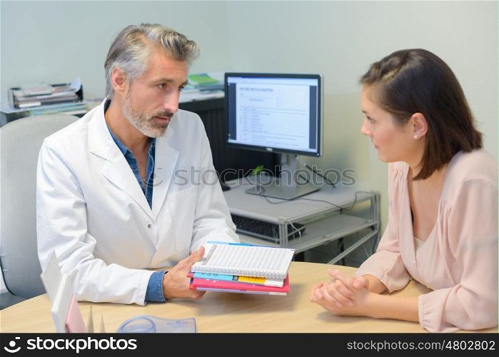 Doctor passing information pack to patient
