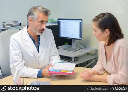 Doctor passing information pack to patient