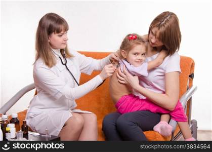Doctor pediatrician examines a sick child at home in the presence of my mother