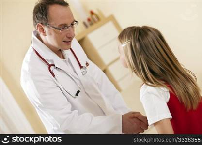 Doctor - Pediatrician - with a child patient in his practice, both are shaking hands