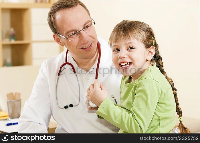 Doctor - Pediatrician - with a child patient in his practice, she is examining his stethoscope, friendly and light atmosphere