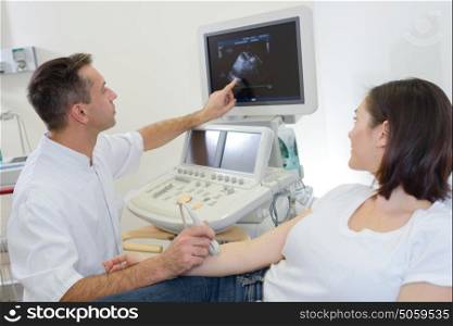 Doctor performing ultrasound explaining findings to patient