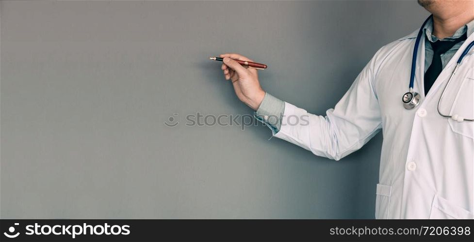 Doctor pointing pen at wall background with copy space.