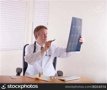 Doctor pointing pen at x-ray chart to show exact location