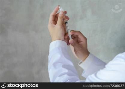 Doctor prepares to administer virus vaccine with syringe.