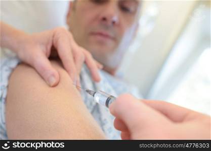 doctor puts syringe in male arm